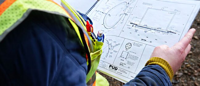 A PUD employee holding a set of water tank engineering plans.