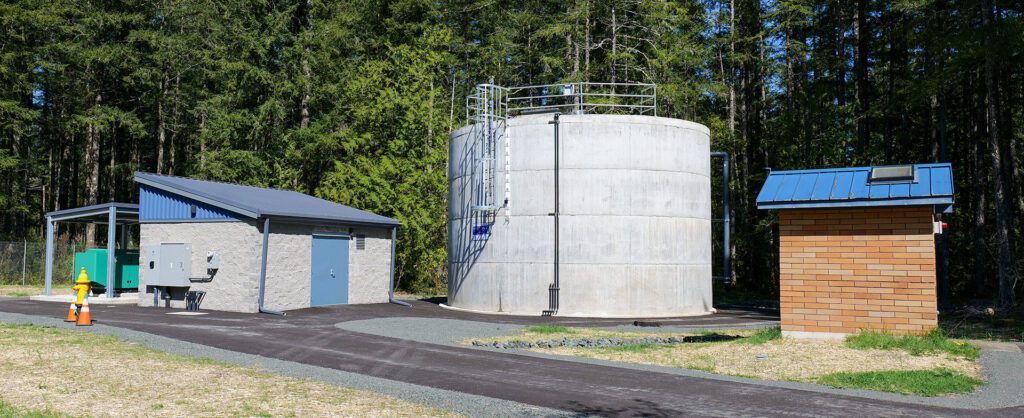 Quilcene's new 105,000-gallon water tank and distribution system (building on left) and the original pump house (brick building on right side of image.