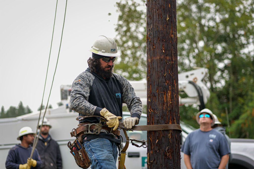 Line Foreman, Jonathan Dehnert secures his climbing gear to the train pole before ascending to perform a rescue.